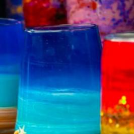 Colorful, abstractly painted glass jars displayed together.