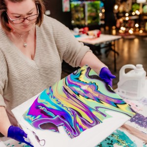 Woman creating colorful abstract art on canvas indoors.