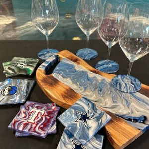 Wine glasses, coasters, and a marbled cheese board on a table.